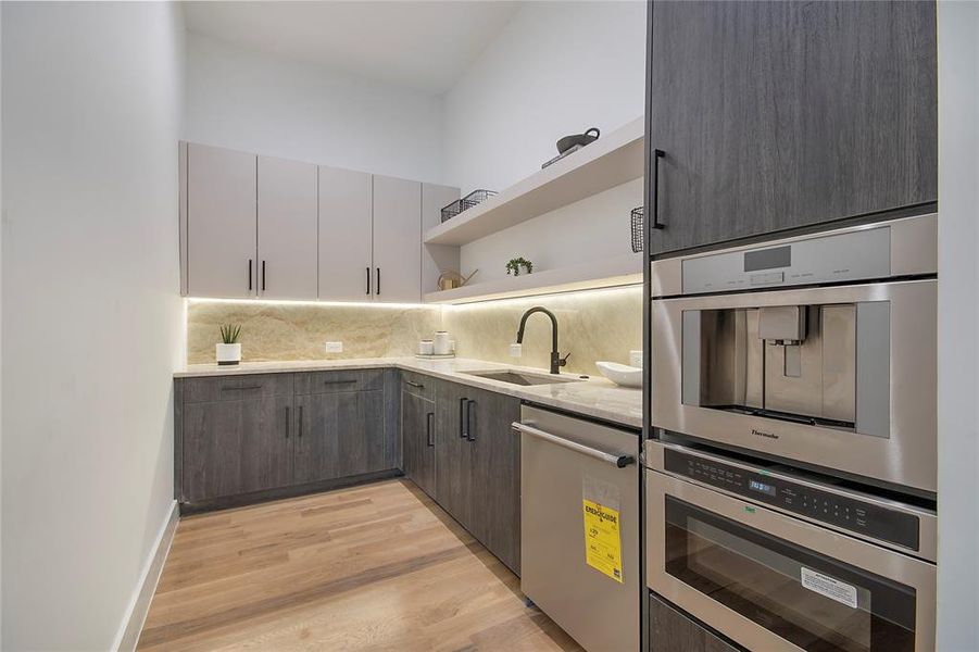 Kitchen with open shelves, appliances with stainless steel finishes, light wood-style flooring, tasteful backsplash, and modern cabinets