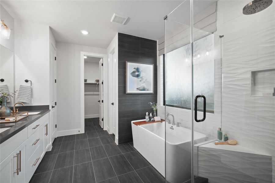 Full bathroom featuring double vanity, tile walls, a stall shower, a spacious closet, and a freestanding tub