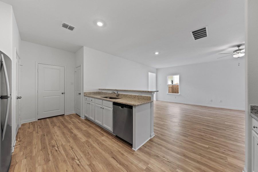 Kitchen with a peninsula, light stone counters, stainless steel appliances, white cabinetry, and open floor plan