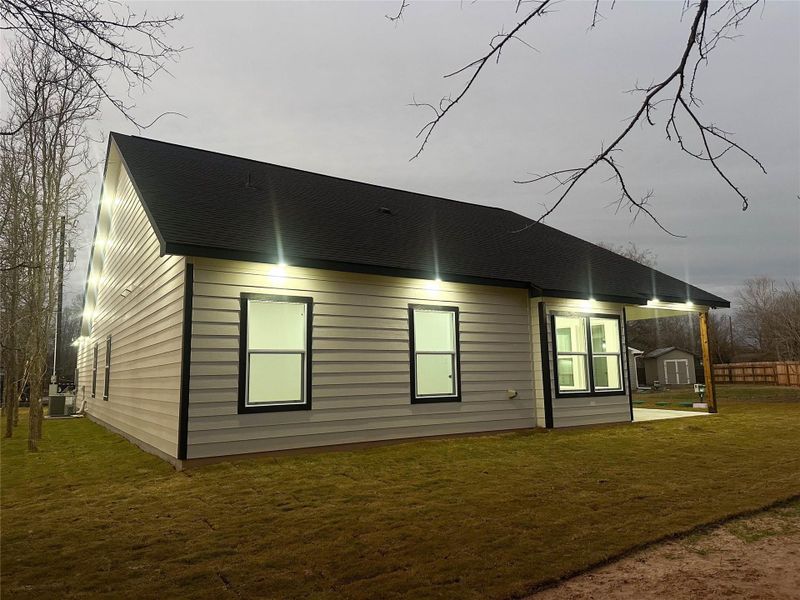 Rear view of property with a lawn, a patio, and a shingled roof