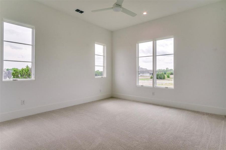 Unfurnished room featuring baseboards, visible vents, a ceiling fan, and light colored carpet