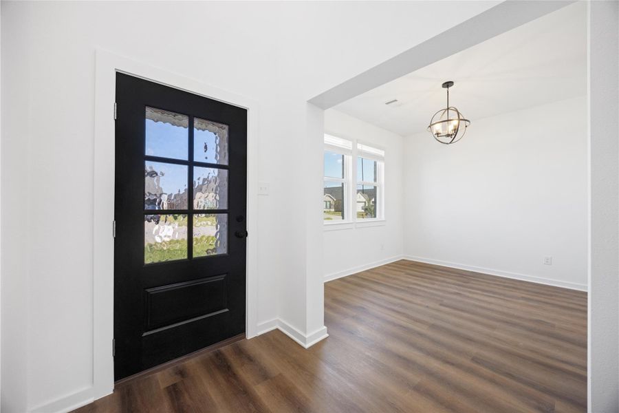 This entryway features a stylish black door with frosted glass panels and leads into a bright room with large windows and elegant wood flooring. A modern light fixture adds a contemporary touch. This entryway features a stylish black door with frosted glass panels and leads into a bright room with large windows and elegant wood flooring. A modern light fixture adds a contemporary touch.