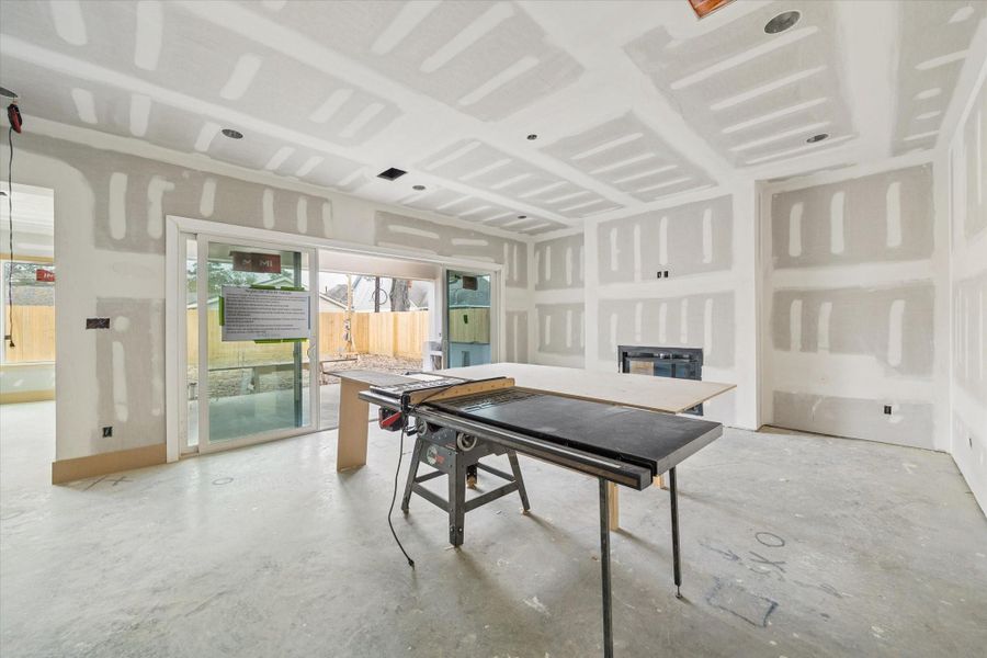 Open living area anchored by a sleek fireplace and oversized sliding glass doors that extend entertaining to the covered patio. Smooth finish walls, recessed lighting, and generous ceiling height create a clean, modern backdrop for this Harvard Homes build in Oak Forest.