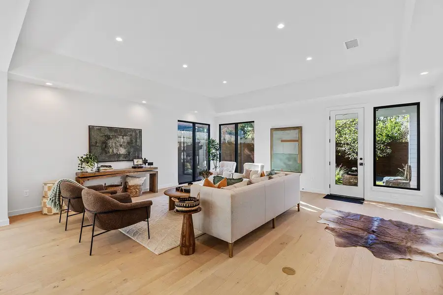 Living room featuring recessed lighting, light wood-style floors, and a raised ceiling