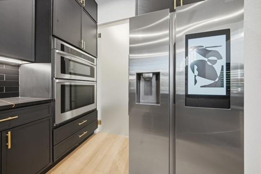 Stainless steel French door refrigerator with integrated display, built-in double oven, and microwave