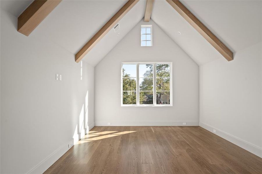 Blending charm and sophistication, this bedroom features soaring vaulted ceilings with exposed stained wood beams, creating a warm and inviting ambiance. A picturesque window floods the space with natural light while offering serene neighborhood views. The rich white oak hardwood floors add timeless elegance, making this bedroom a perfect retreat.