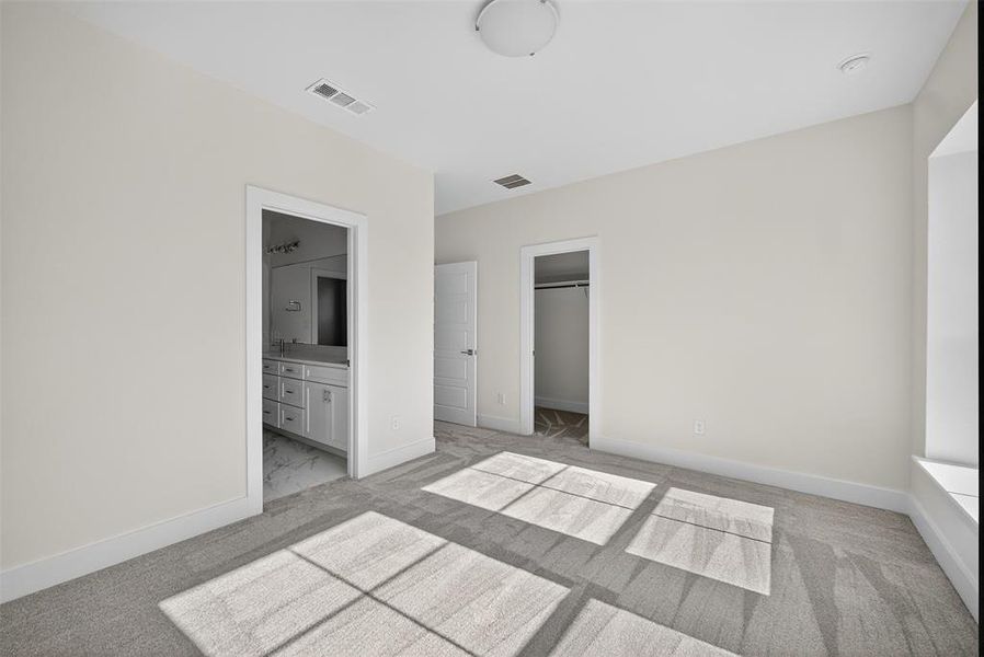 Unfurnished bedroom with light carpet and connected bathroom Unfurnished bedroom with light carpet and connected bathroom
