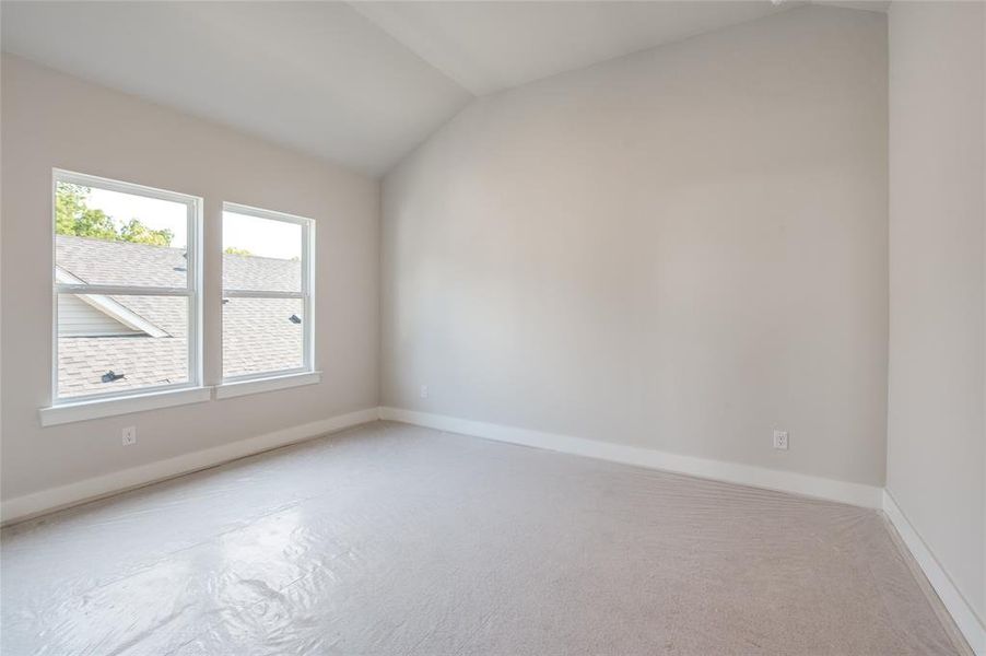 Carpeted spare room with lofted ceiling