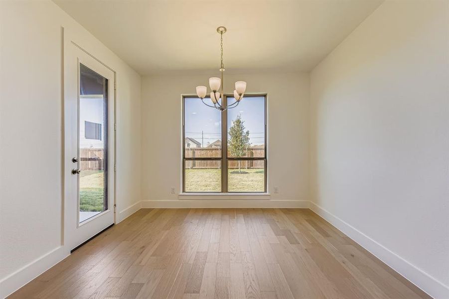 Unfurnished dining area featuring light wood-style flooring and a chandelier Unfurnished dining area featuring light wood-style flooring and a chandelier
