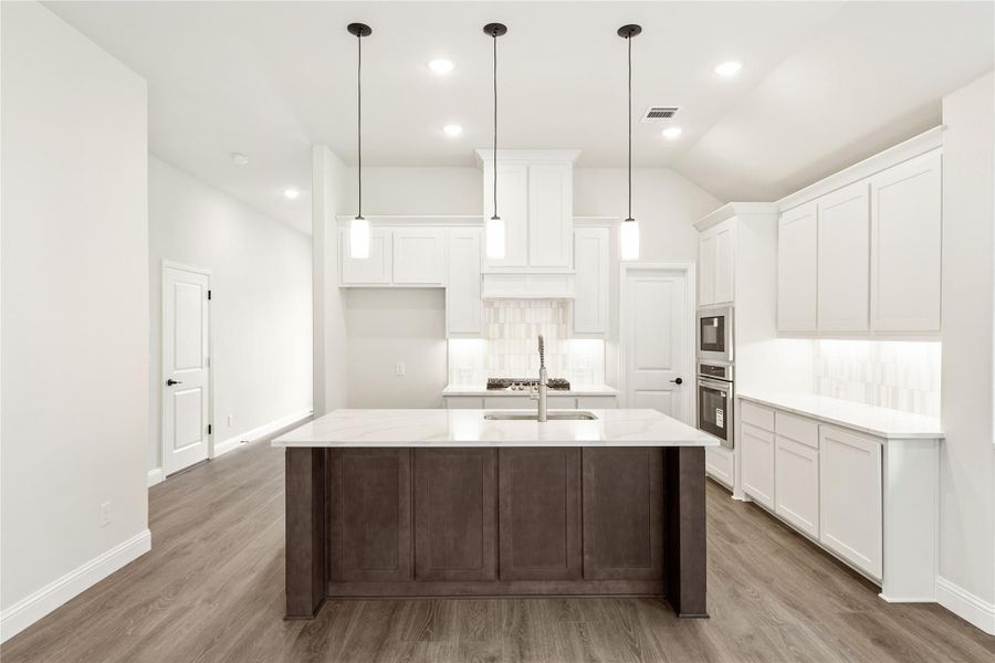 Kitchen with large dark wood island, white cabinets, pendant lights, and hardwood floors Kitchen with large dark wood island, white cabinets, pendant lights, and hardwood floors
