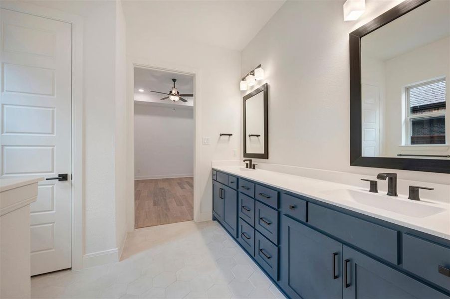 Well-appointed bathroom featuring a double vanity with dark blue cabinetry, white countertops, and black fixtures
