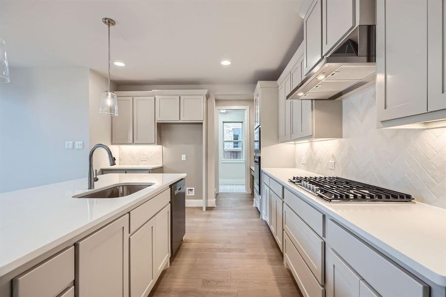 Kitchen featuring recessed lighting, decorative light fixtures, tasteful backsplash, light countertops, and light wood-style flooring