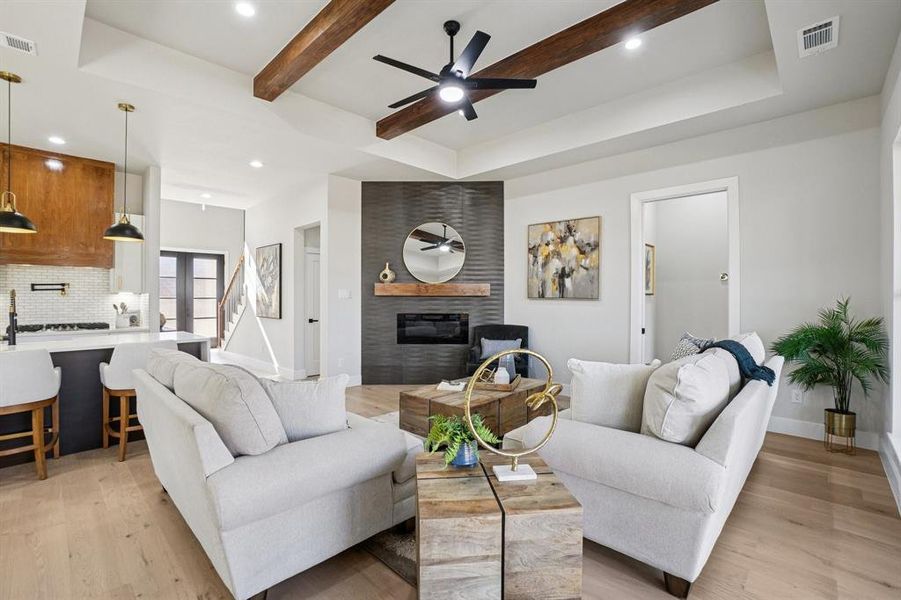 Living room featuring recessed lighting, ceiling fan, a fireplace, light wood-style floors, and beam ceiling