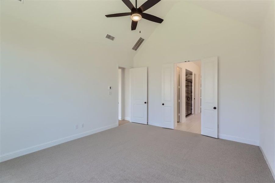 Unfurnished bedroom with high vaulted ceiling, light carpet, and ceiling fan