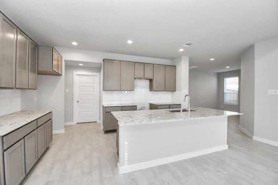 Culinary haven, featuring granite countertops, a tile backsplash, stainless steel appliances (to be installed), and 42” upper cabinets. Sample photo of completed home with similar floor plan. Actual colors and selections may vary.