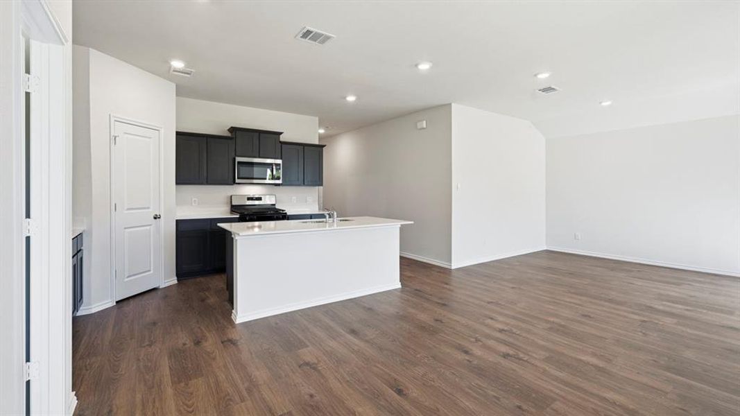 Kitchen featuring a center island with sink, appliances with stainless steel finishes, recessed lighting, open floor plan, and dark wood-type flooring Kitchen featuring a center island with sink, appliances with stainless steel finishes, recessed lighting, open floor plan, and dark wood-type flooring