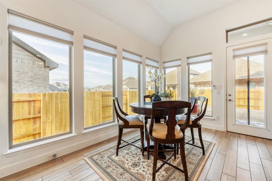 Sunroom featuring wood finished floors, vaulted ceiling, and a residential view
