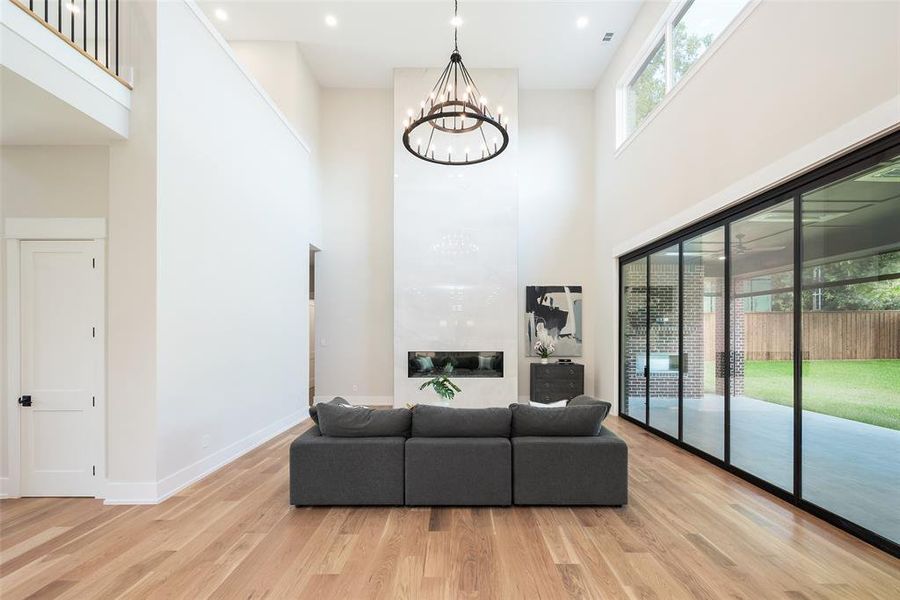 Living room with a towering ceiling, an inviting chandelier, and light wood-type flooring