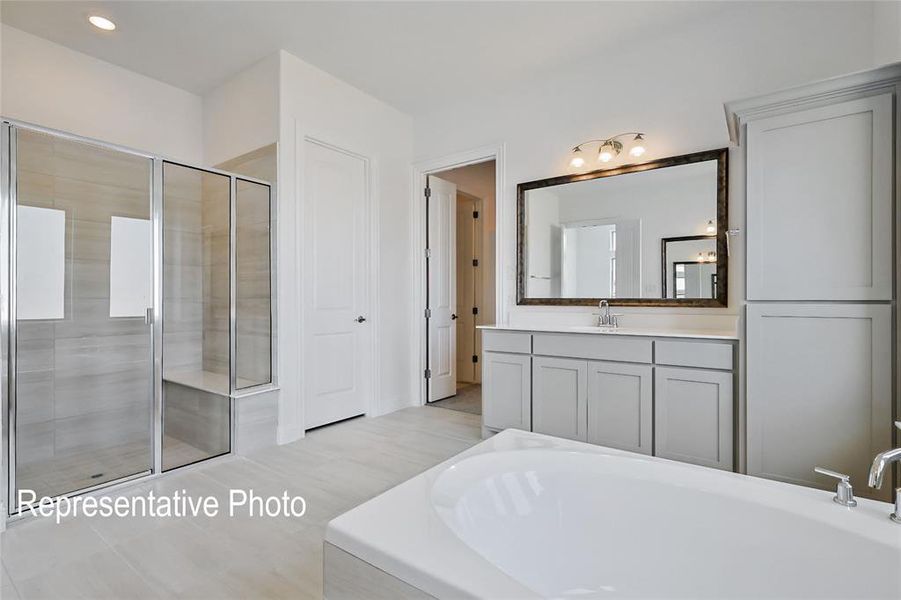 Spacious bathroom featuring a frameless glass shower enclosure with a built-in bench, a separate soaking tub, and a vanity with a large framed mirror