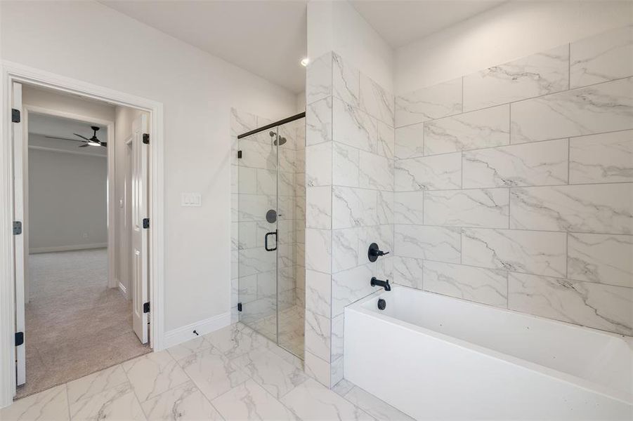 Bathroom with a tub, a shower stall, ceiling fan, and marble look tiles