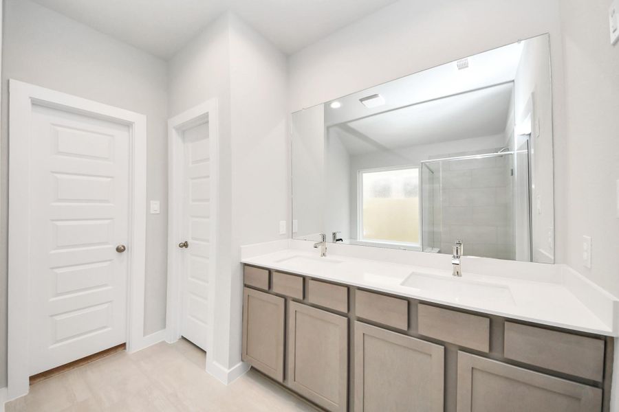Elevate your daily routine at the elegant vanity, now equipped with double sinks, light countertops, modern hardware, and beautiful recessed lights. Sample photo of completed home with similar floor plan. Actual colors and selections may vary.