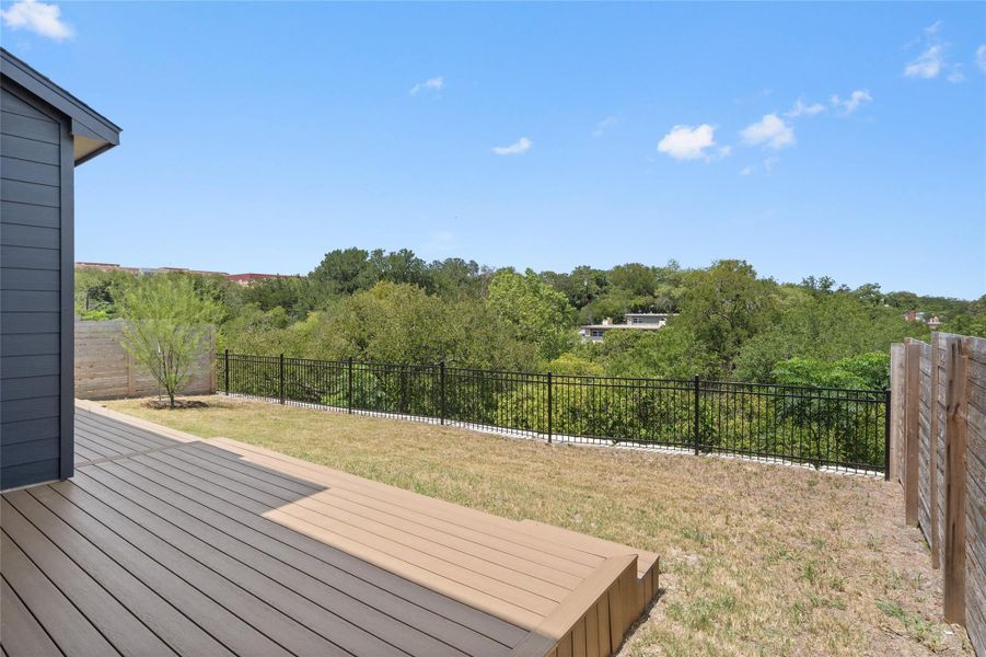 A spacious backyard with a composite deck offers tranquil tree-filled views under a bright sky. A spacious backyard with a composite deck offers tranquil tree-filled views under a bright sky.