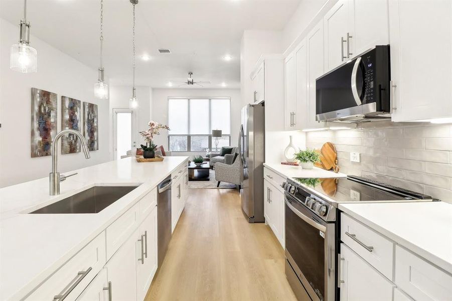 Kitchen with light countertops, appliances with stainless steel finishes, open floor plan, a sink, and light wood-type flooring