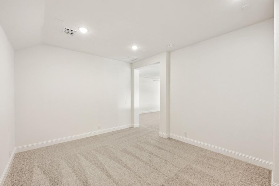 Empty room with white walls, beige carpet, recessed lighting, and open doorway to adjacent space