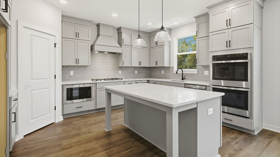 Kitchen with quartz countertops, tile backsplash, and pendant lighting
