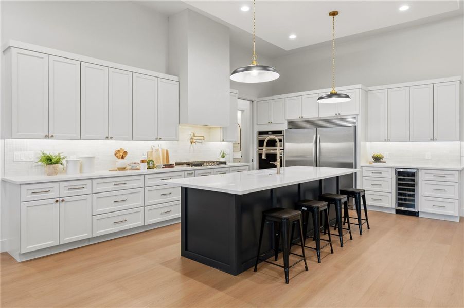Kitchen featuring white cabinetry, hanging light fixtures, a towering ceiling, a breakfast bar area, and recessed lighting