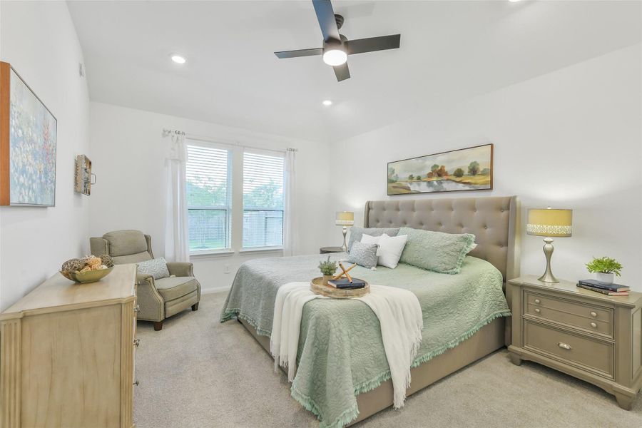 This generous primary bedroom has room for a king size bed and additional seating. Windows with blinds for privacy look out into the backyard.