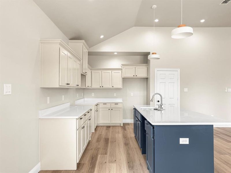 Kitchen with a ceiling fan, hanging light fixtures, open floor plan, lofted ceiling, and light wood-type flooring