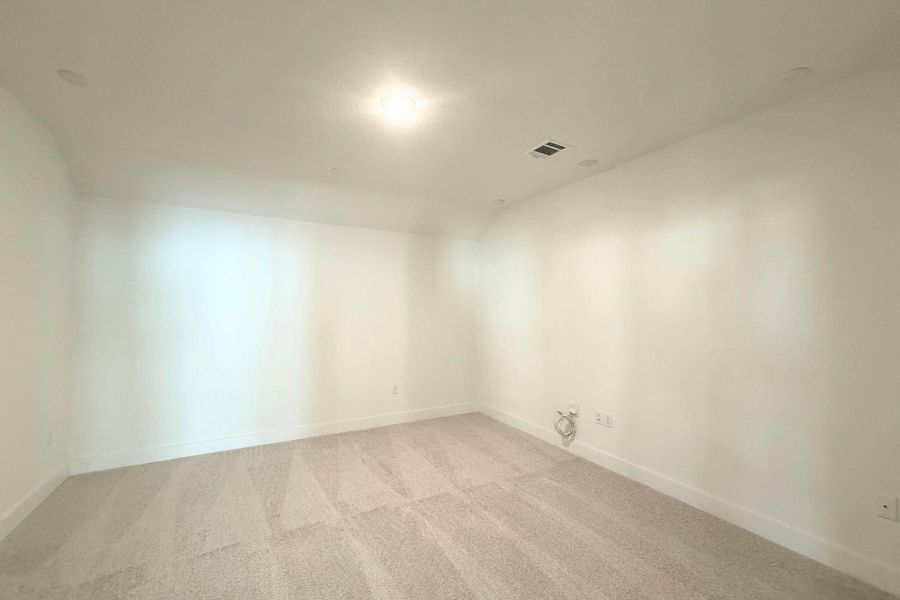 A spacious, neutral-toned room awaiting your personal touch, featuring soft carpeting and abundant overhead lighting. A spacious, neutral-toned room awaiting your personal touch, featuring soft carpeting and abundant overhead lighting.