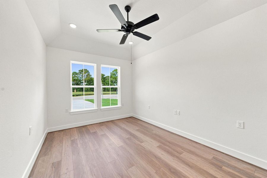 Bright home office/study with wood-look flooring, ceiling fan, and large windows—ideal for working from home, reading, or hobbies.