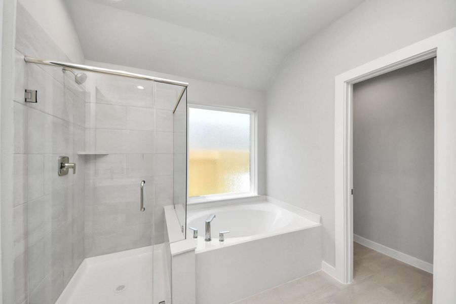 Escape to a spa-like oasis in this primary bathroom. Enjoy a walk-in shower with tile surround, a separate garden tub with custom detailing, and an elegant vanity featuring light countertops, modern hardware, and beautiful recessed lights. Experience luxury and relaxation in every detail. Sample photo of completed home with similar floor plan. Actual colors and selections may vary. Escape to a spa-like oasis in this primary bathroom. Enjoy a walk-in shower with tile surround, a separate garden tub with custom detailing, and an elegant vanity featuring light countertops, modern hardware, and beautiful recessed lights. Experience luxury and relaxation in every detail. Sample photo of completed home with similar floor plan. Actual colors and selections may vary.