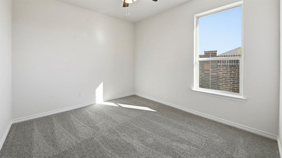 Carpeted spare room with ceiling fan and baseboards
