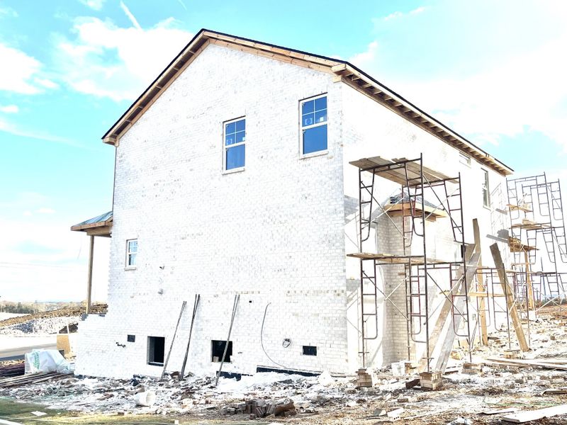 4 sides white brick with black shutters and grey stone accent.