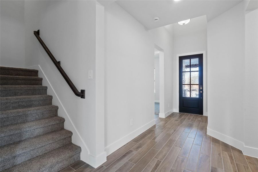 The eye is drawn to the stylish carpeted staircase, complete with a sleek black iron handrail, offering a seamless transition to the home's upper level and highlighting the welcoming foyer that sets a sophisticated tone for the entire residence. The eye is drawn to the stylish carpeted staircase, complete with a sleek black iron handrail, offering a seamless transition to the home's upper level and highlighting the welcoming foyer that sets a sophisticated tone for the entire residence.