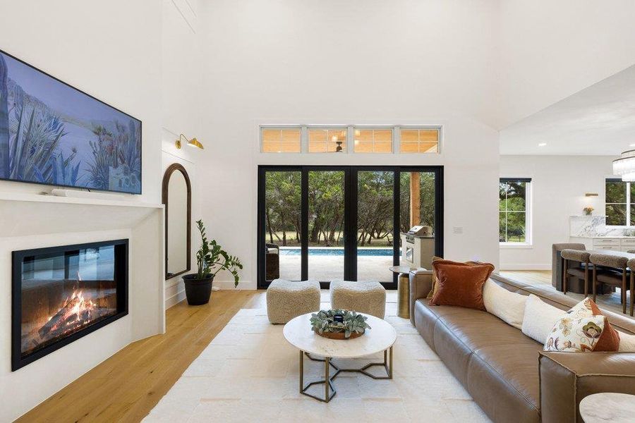 A spacious living area with a modern fireplace transitions seamlessly to an inviting outdoor pool through elegant glass doors. A spacious living area with a modern fireplace transitions seamlessly to an inviting outdoor pool through elegant glass doors.
