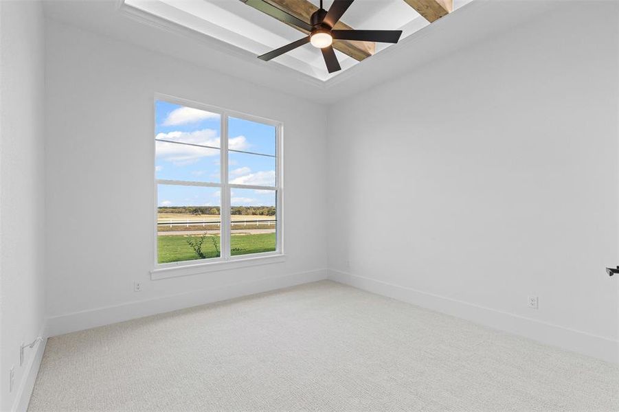 Empty room featuring beam ceiling, a ceiling fan, and light carpet