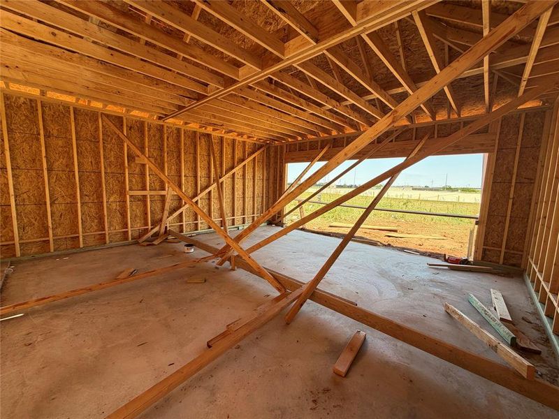 New construction framing with wood studs, plywood sheathing, and a concrete slab floor