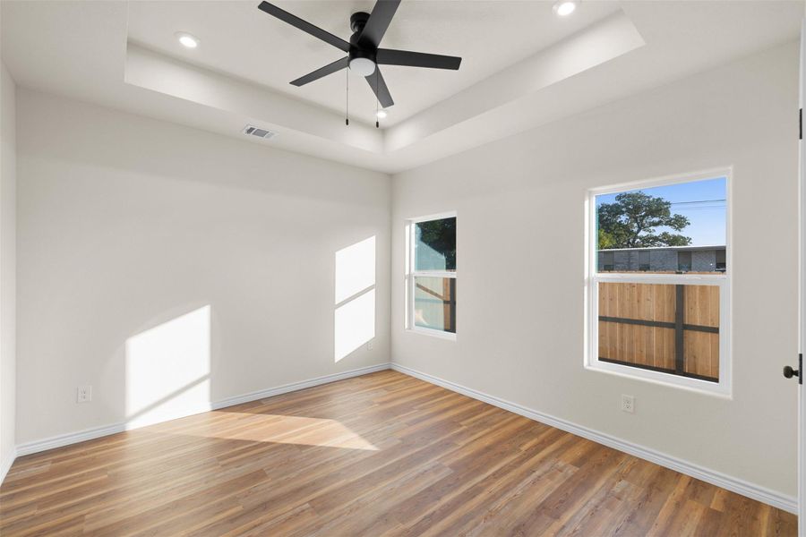 Unfurnished room featuring light wood-type flooring, a tray ceiling, recessed lighting, and a ceiling fan Unfurnished room featuring light wood-type flooring, a tray ceiling, recessed lighting, and a ceiling fan