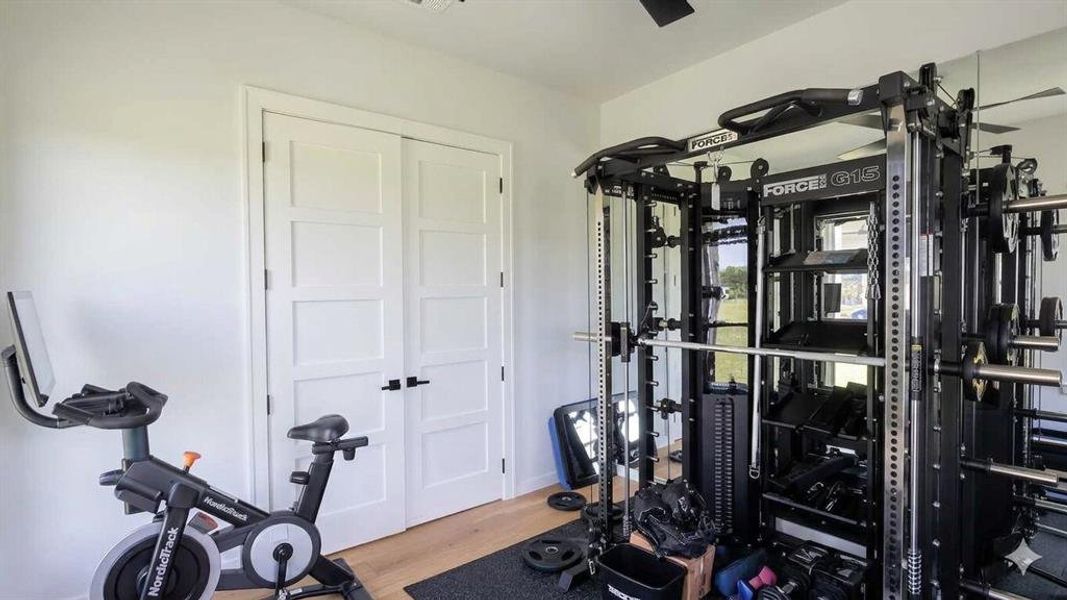 Room featuring wood-finish flooring, white walls, and a ceiling fan