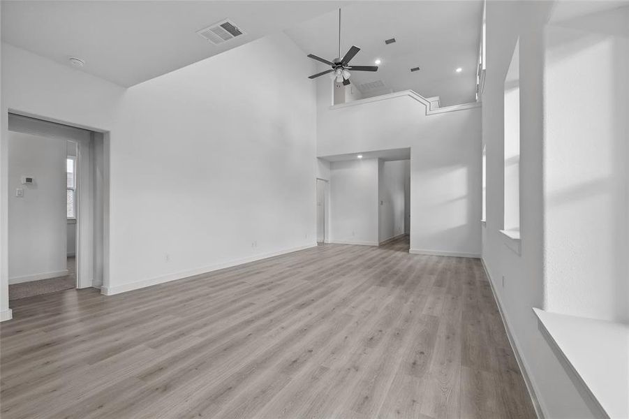 Unfurnished living room featuring high vaulted ceiling, light wood-style flooring, ceiling fan, and recessed lighting
