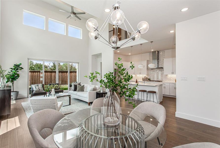 Living room featuring a healthy amount of sunlight, hardwood / wood-style flooring, ceiling fan with notable chandelier, and a high ceiling