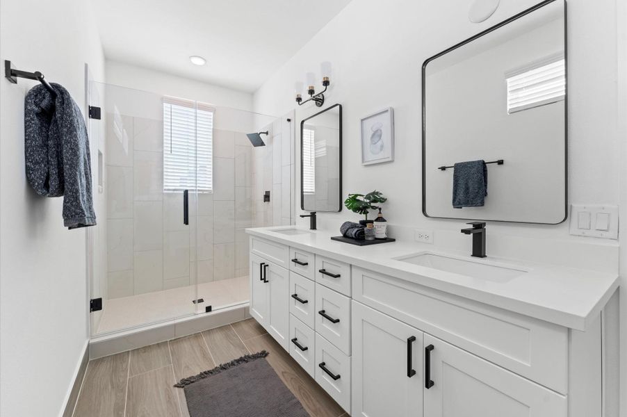 Step into spa-inspired luxury in this primary bathroom, where a sleek walk-in shower takes center stage. Framed by frameless glass and accented with sleek tilework, the shower features dual rainfall showerheads and a built-in bench for ultimate comfort. A quartz vanity with double sinks and independent mirrors adds modern elegance, while soft ambient lighting and neutral tones create a calming retreat just steps from the bedroom. Step into spa-inspired luxury in this primary bathroom, where a sleek walk-in shower takes center stage. Framed by frameless glass and accented with sleek tilework, the shower features dual rainfall showerheads and a built-in bench for ultimate comfort. A quartz vanity with double sinks and independent mirrors adds modern elegance, while soft ambient lighting and neutral tones create a calming retreat just steps from the bedroom.