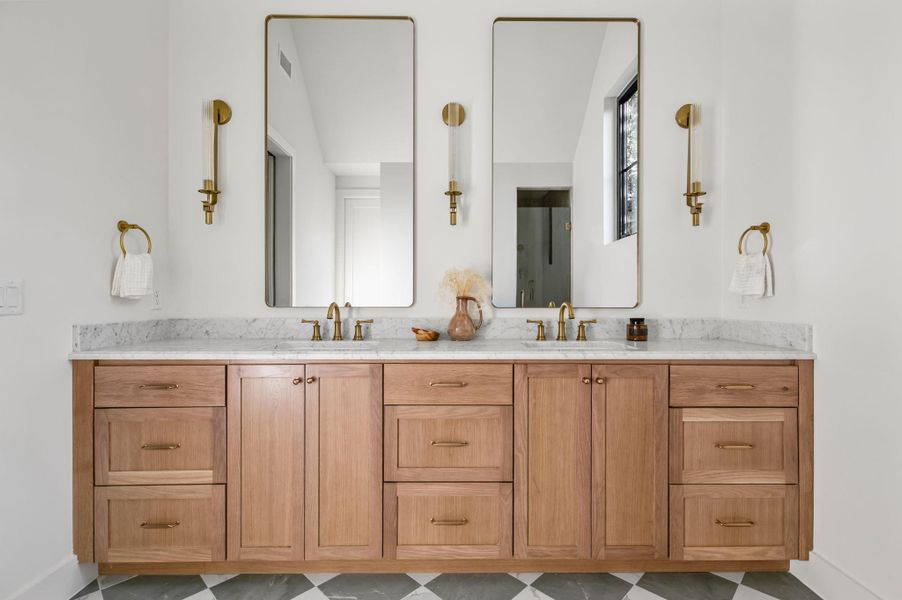 Marble countertops and rich wood cabinetry adorn this dual-sink vanity in a bright, modern bathroom.