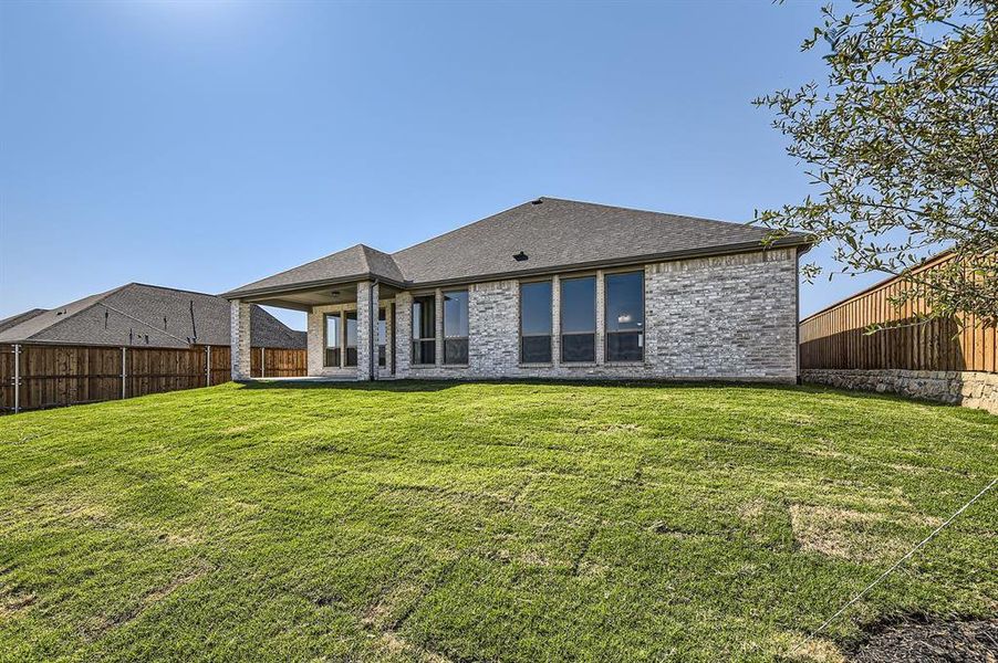 Rear view of property featuring a lawn and a patio