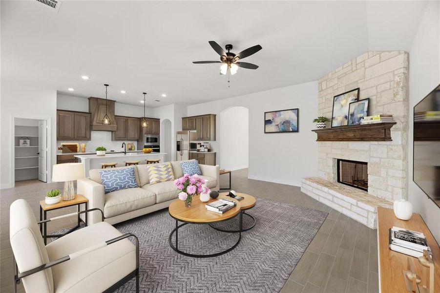 Living room featuring recessed lighting, a stone fireplace, arched walkways, light wood-style floors, and ceiling fan Living room featuring recessed lighting, a stone fireplace, arched walkways, light wood-style floors, and ceiling fan
