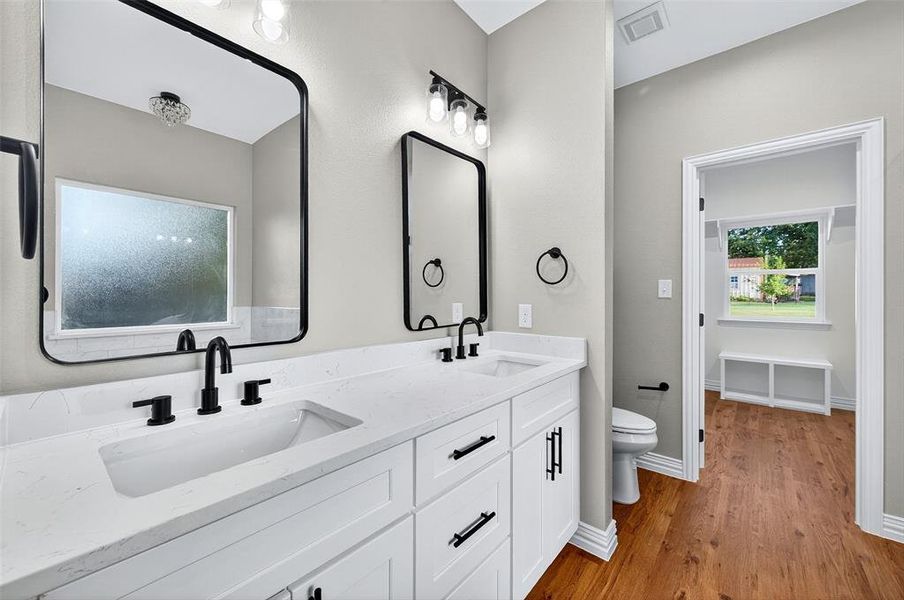 Bathroom featuring light wood finished floors and double vanity Bathroom featuring light wood finished floors and double vanity